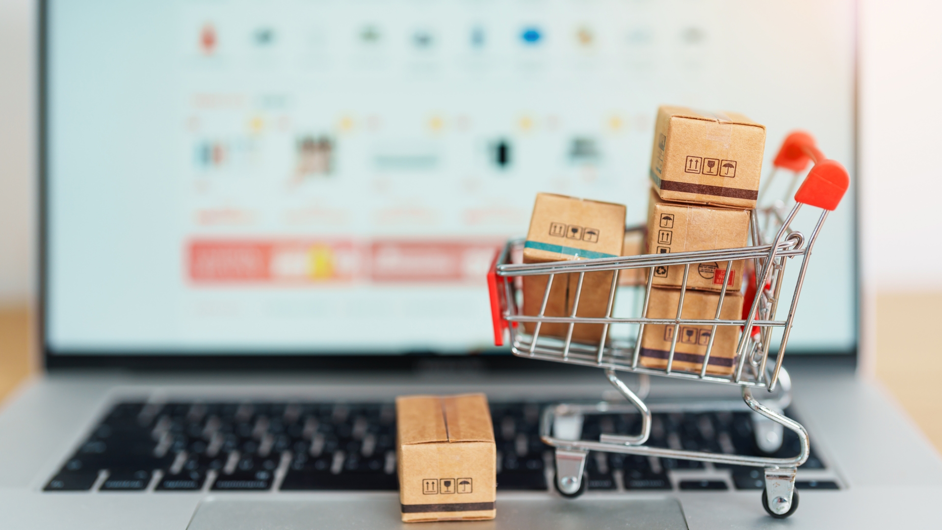 Five Essential Elements Of An Ecommerce Website Matrix Internet A miniature shopping cart filled with small boxes sits on a laptop keyboard