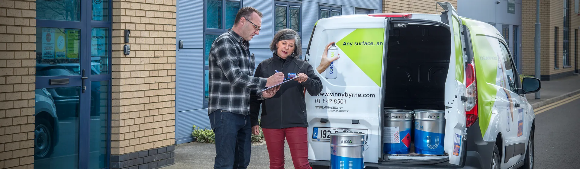 Two people discussing a paint delivery order beside the delivery van