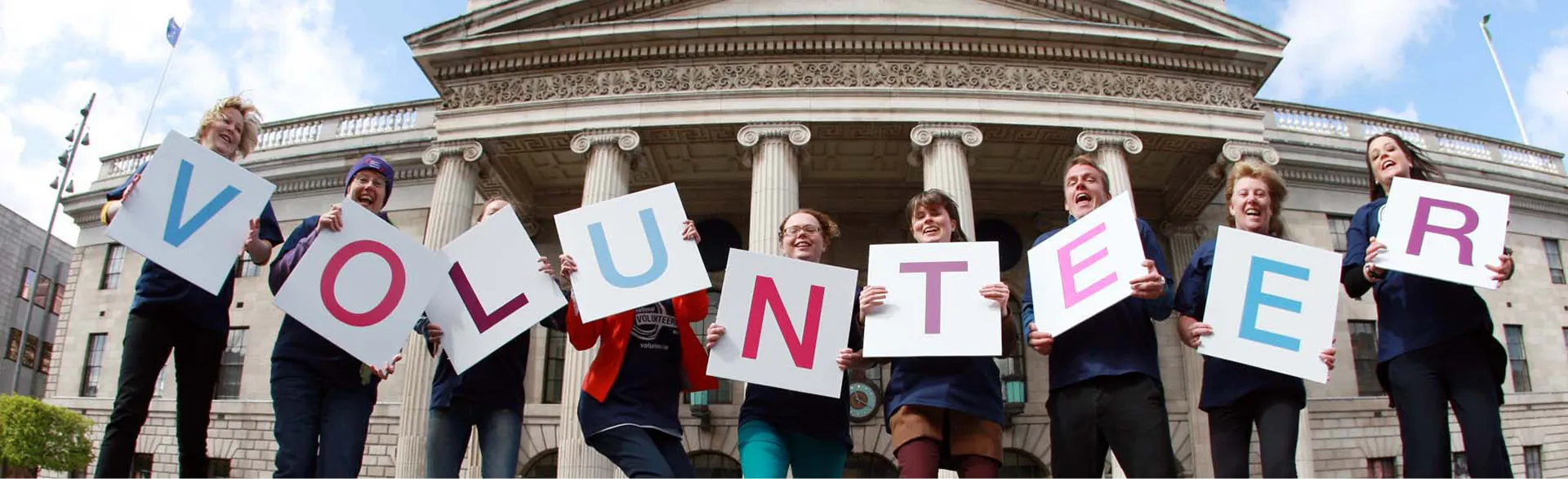 People all carrying a letter which, together, spell "volunteer"