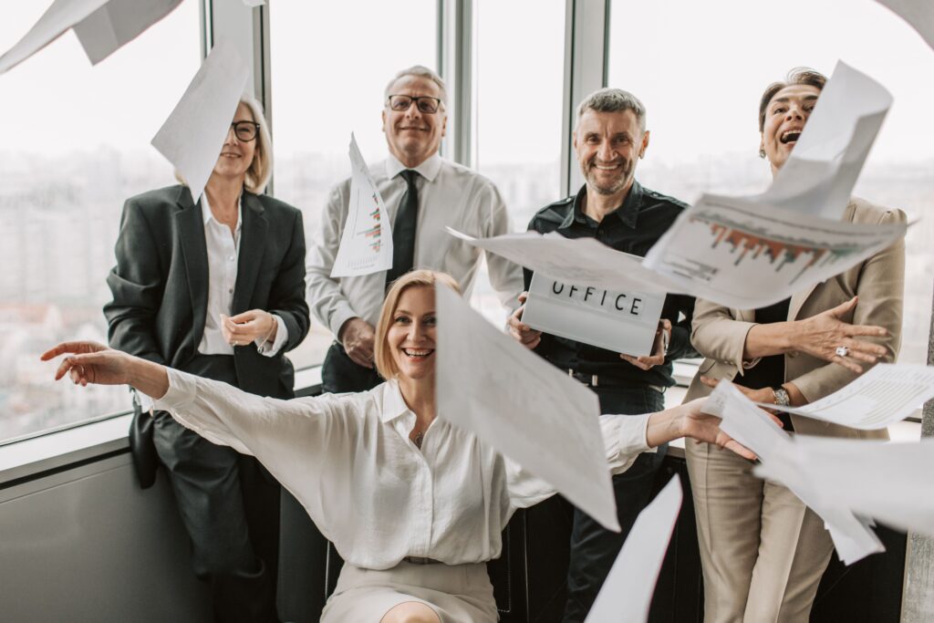We're all still at it. The lasting grip of weird business language Matrix Internet Business team celebrating in an office as papers fly through the air.